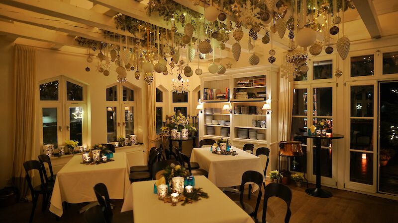 Weihnachtlich geschmückter Raum mit drei gedeckten Tischen